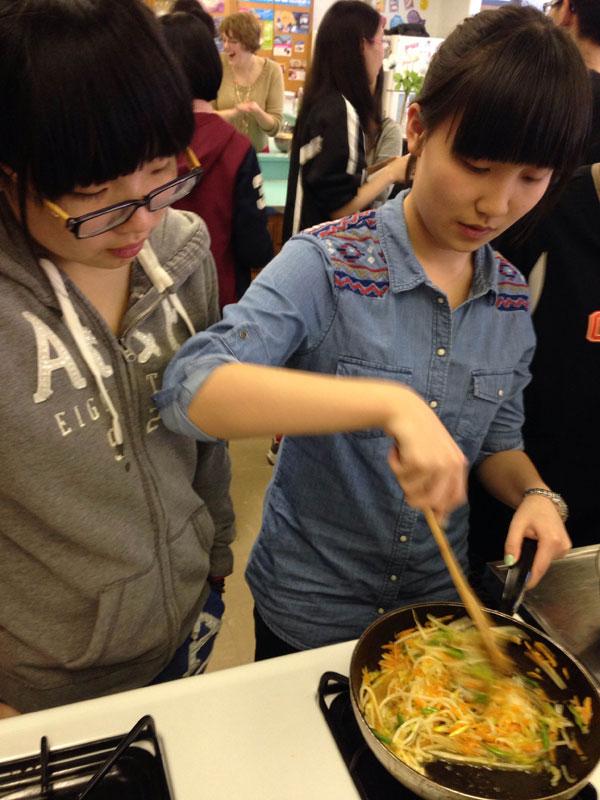 Chinese exchange student Cloris Paranzino watches as fellow exchange student Letty Jackson fries an assortment of vegetables to make Lo Mein at the Feb. 26. Chinese Club meeting.   