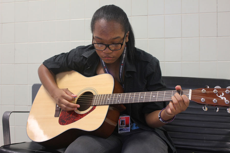 Junior Kayla Heath practices her guitar outside of room M-1 on Sept. 5 while wearing her ID card.