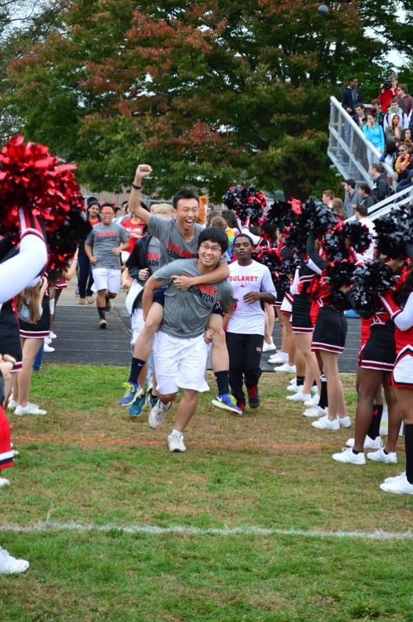 Senior Steven Zhang carries junior Yiyi Kuang as the badminton team runs out to “Twilight Zone” by the band 2 Unlimited at the Oct. 10 pep rally. 
