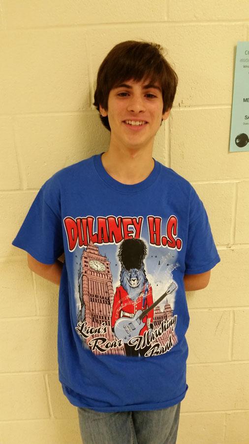 Junior Gustavo Encarnacion sports his new Marching Band show shirt that displays the bands enthusiasm as they go to London to play in their New Years Parade on October 10. This is also the shirt that Marching Band will wear during their performance at the Pep Rally.