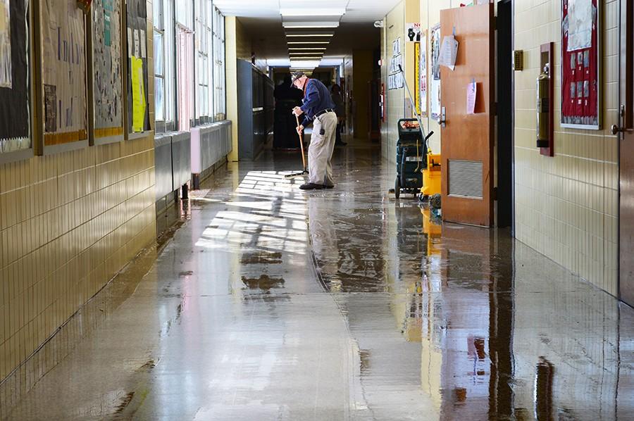 Custodian Bill Underwood sweeps water into the courtyard following a pipe burst in the main hallway Feb. 18. The flood was the second that day. Friends of Dulaney cite pipe bursts, termite infestation and temperature fluctuations, among other building issues, as evidence to prove that renovations are needed.