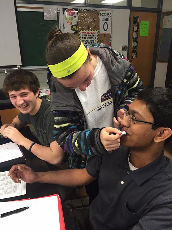 Senior Bennett Heitt watches with anxiety as senior Casey Proefrock puts lipstick on fellow classmate and senior Maroof Neebir. This was part of a forensics lab where students learned how to analyze lip prints.