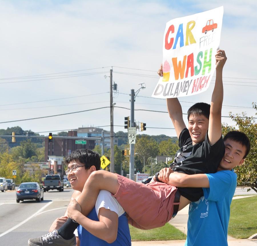 Seniors Vincent Song and Steven Zhang, and Towson High School junior Rui Fu hold up a sign to inform passing cars about the Key Club Car Wash. The 