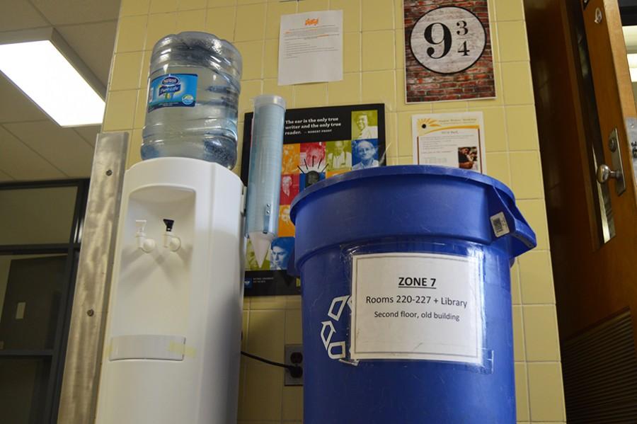 A water bubbler with its corresponding recycling bin outside of room 300.