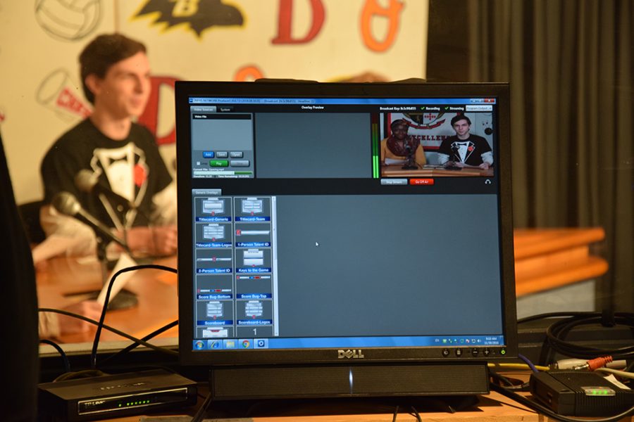 A monitor in the morning announcements room shows the new program, NewTek Tricaster, on screen. The program allows student broadcasters to view anchors as they deliver the morning announcements (see: senior Daniel Longest both behind the monitor and on the screen).